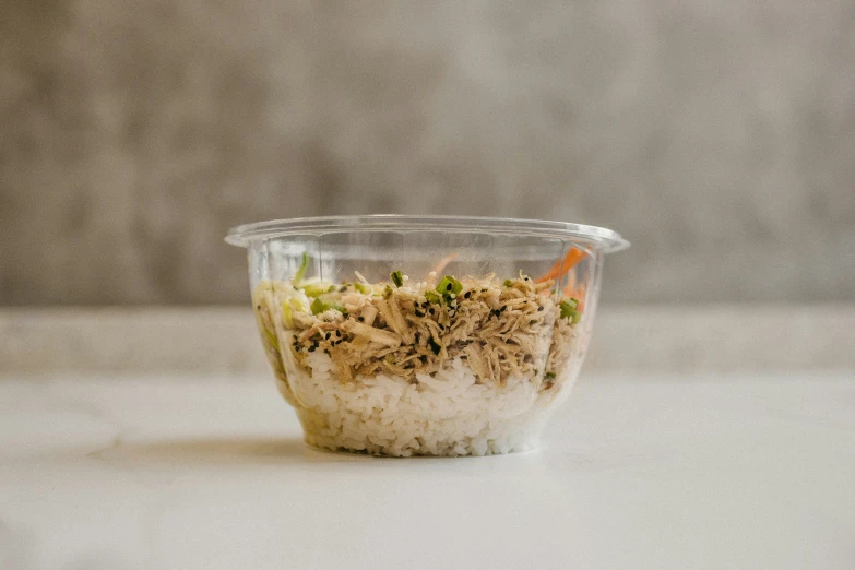 a plastic container full of rice, vegetables, and spices