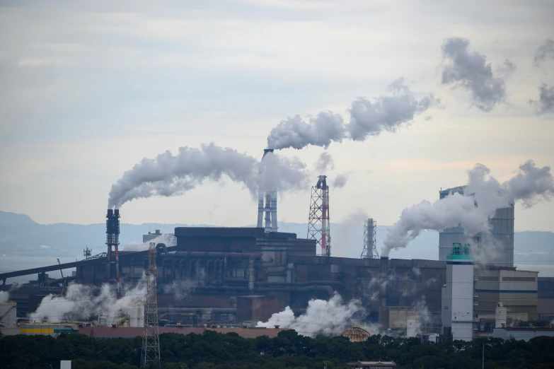 smoke pouring out of stacks of industrial buildings