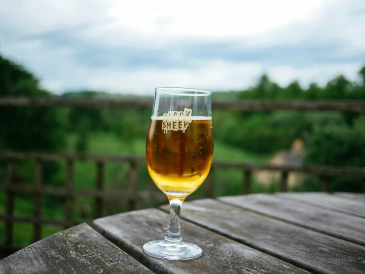 a glass of beer on top of a wooden table