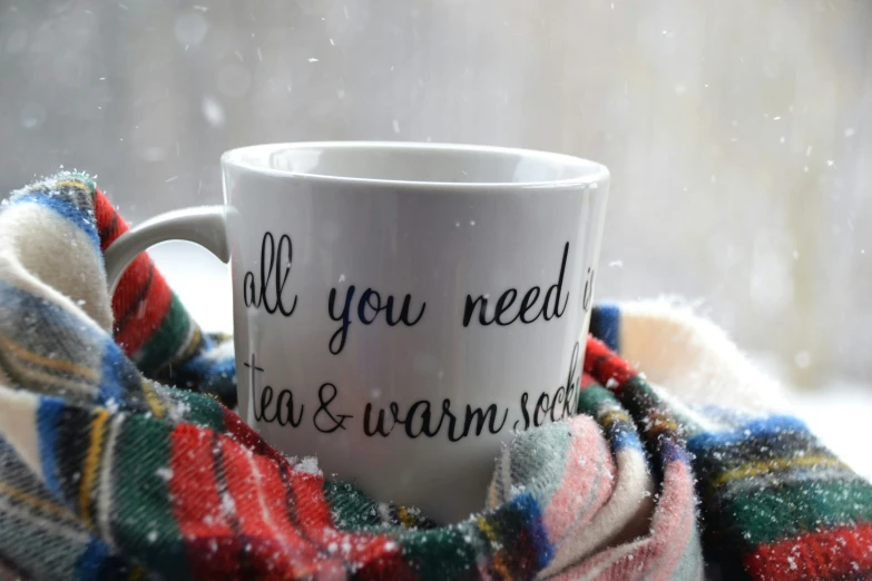 the word'all you need is tea and warm wool written on a mug next to a blanket