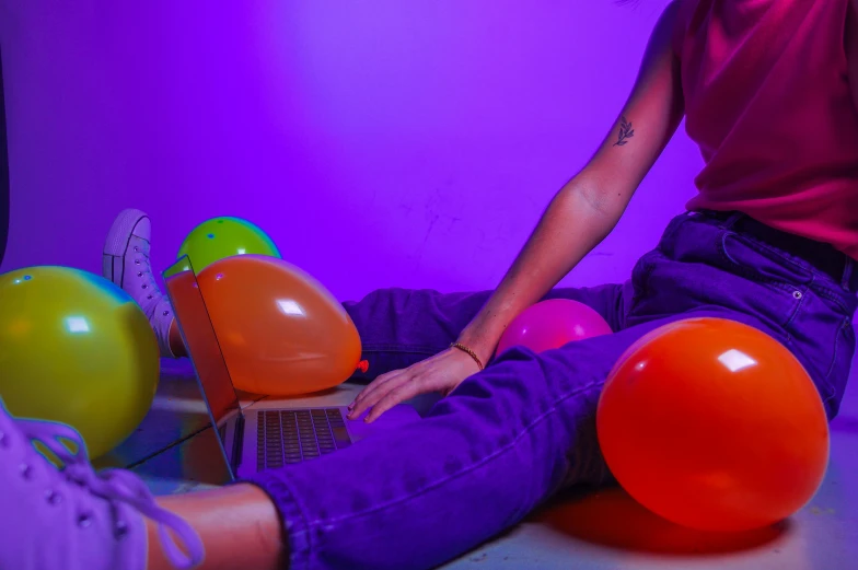 a woman sits on a laptop with balloons