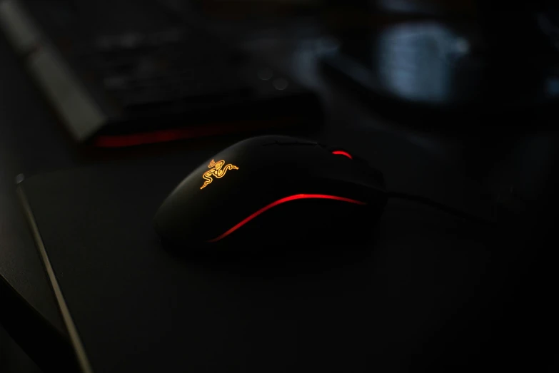 a black computer mouse sitting on a desk next to a keyboard