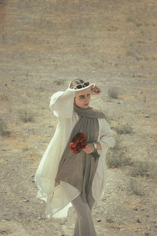 a woman is walking through the desert carrying flowers