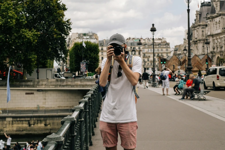 man taking picture while wearing a hat while standing near a street