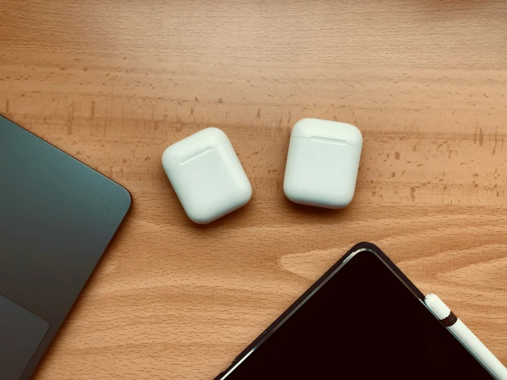 an ipad with an apple airpods, next to it on a desk