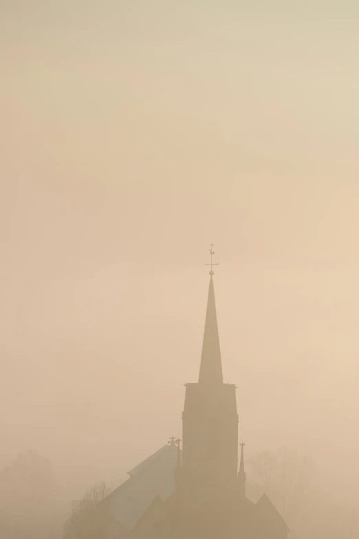 a church spire in the fog on an overcast day