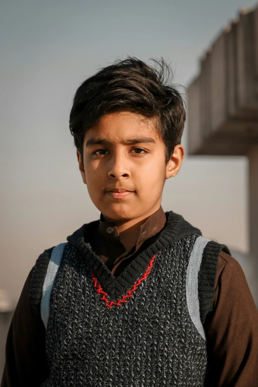 a  wearing a sweater vest in front of a structure