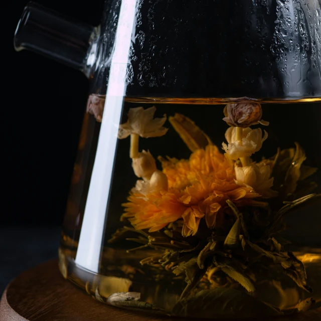 a glass tea pot full of yellow flowers