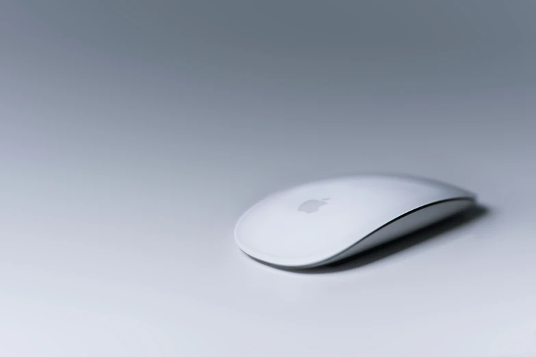 an apple mouse sitting on top of a white desk