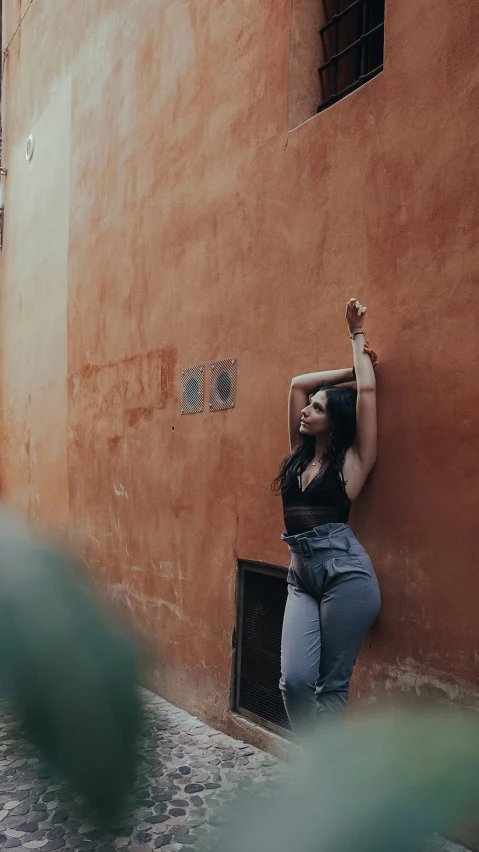 the woman poses with her hand up against a wall