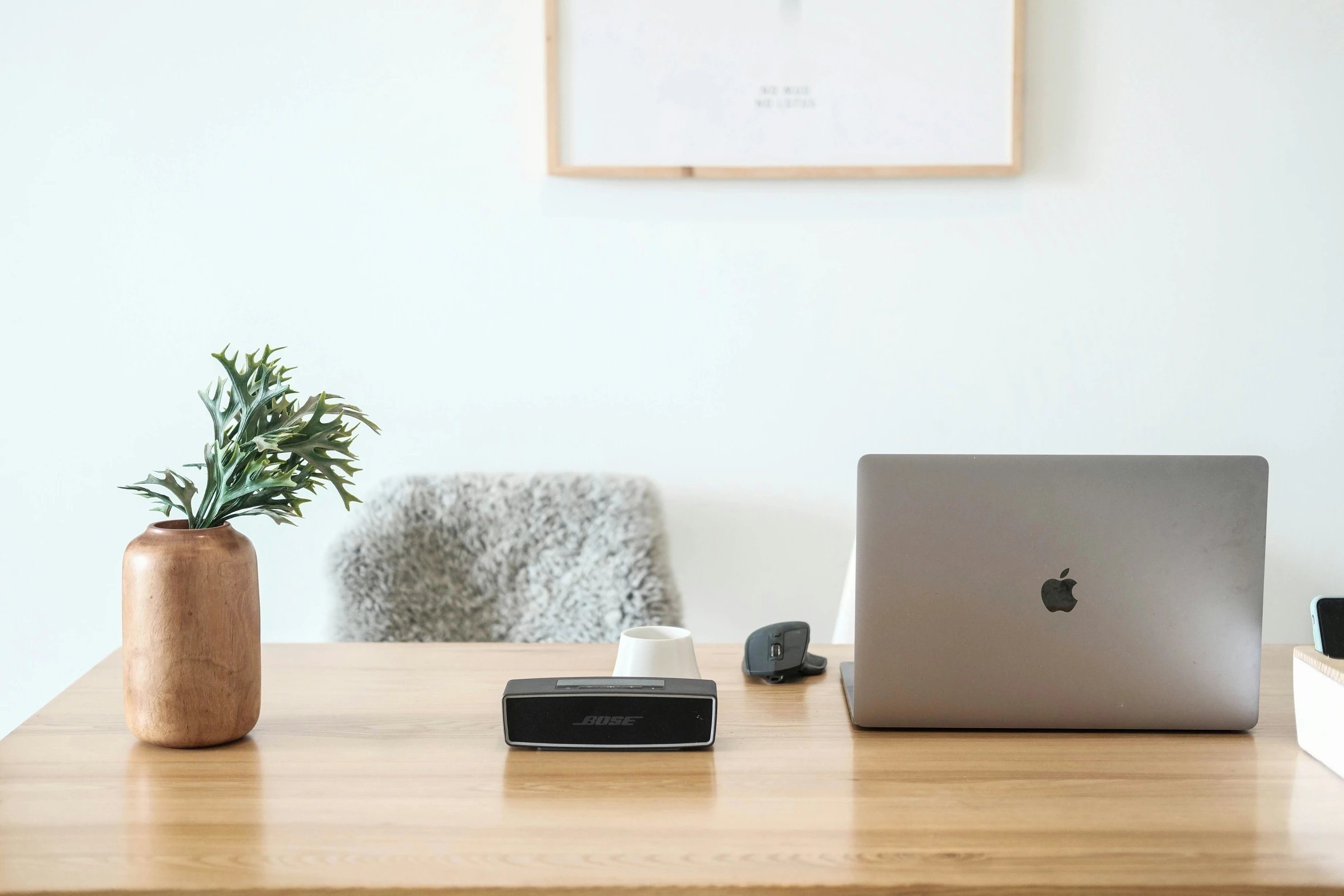 two lap tops on a desk with a phone and a pen