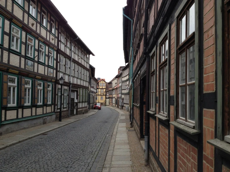 a stone street between two buildings has multiple windows