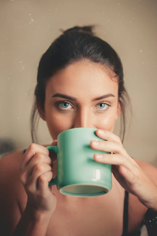 woman in black  with green mug drinking from cup