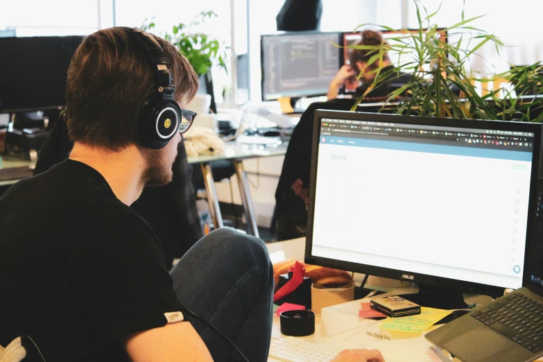 a man is using headphones and sitting at his desk