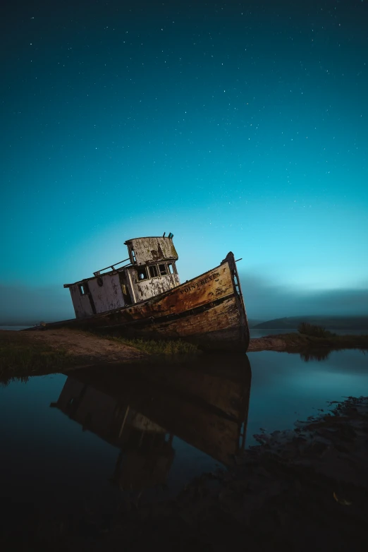 old boat sitting on shore at night with stars shining in sky