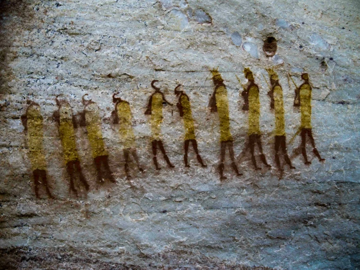 group of people depicted in rock art on a wall