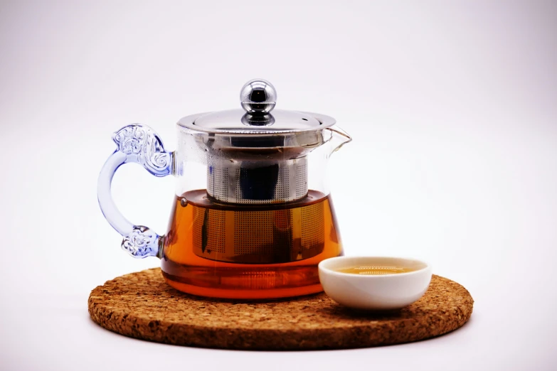 teapot and mug sitting on top of a wooden coaster