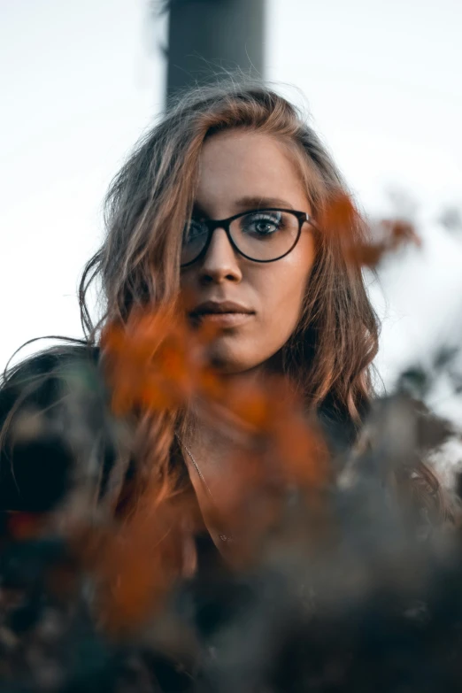 a woman wearing glasses is shown through flowers