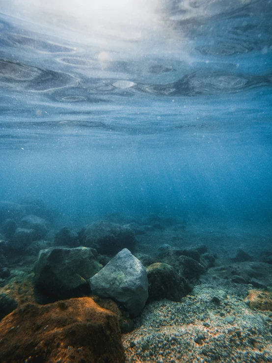 the sky is above the water and rocks below it