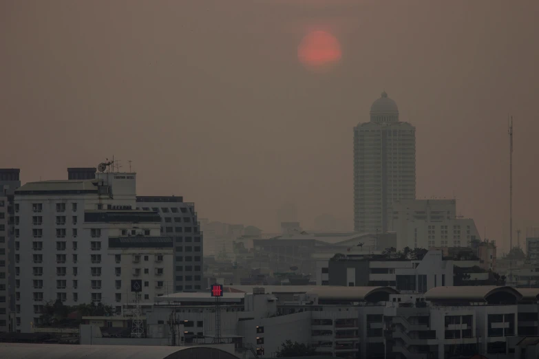 the sun peeks through the hazy sky in a city