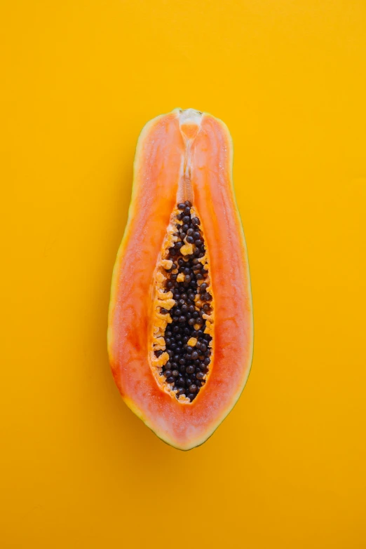 half a papayas fruit on a yellow background