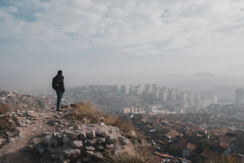 a person standing on top of a cliff looking at a city