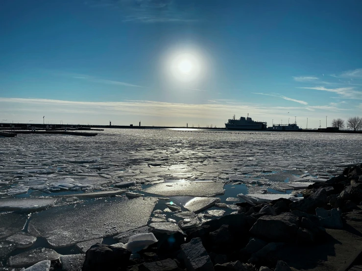 the sun shines on the ice around the water