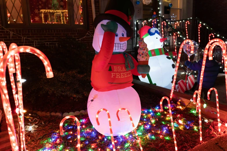 a snowman and christmas lights with a man in an orange sweater