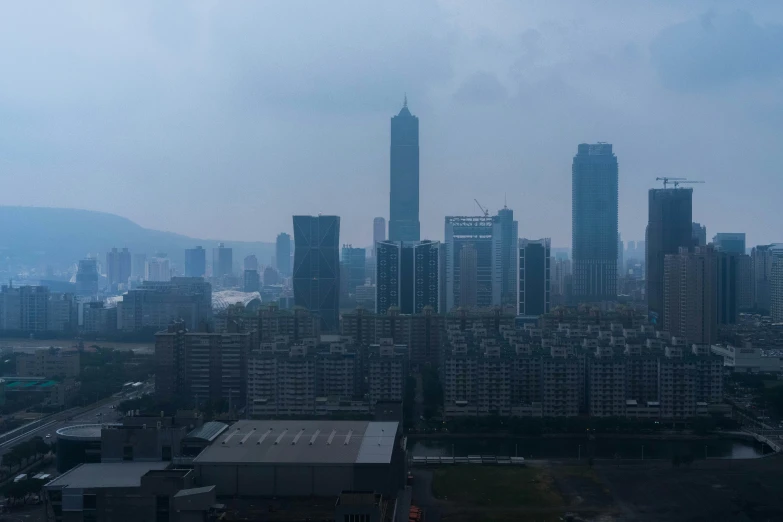 a cityscape with tall buildings, a lake and hills behind it