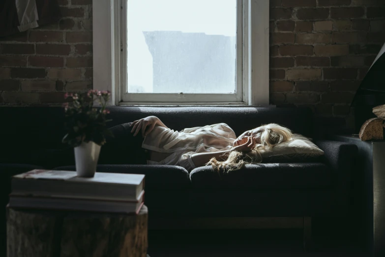 a woman laying on top of a black couch