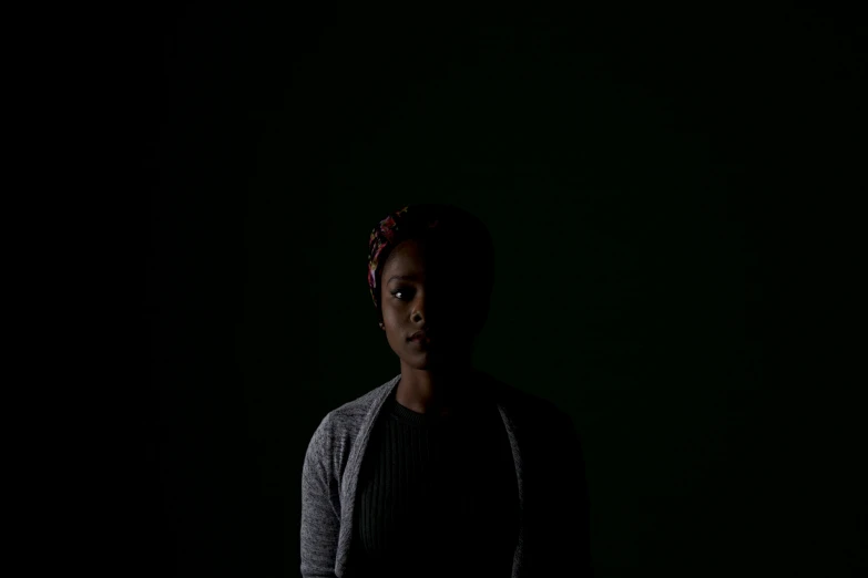 a young woman standing in the dark with her eyes open