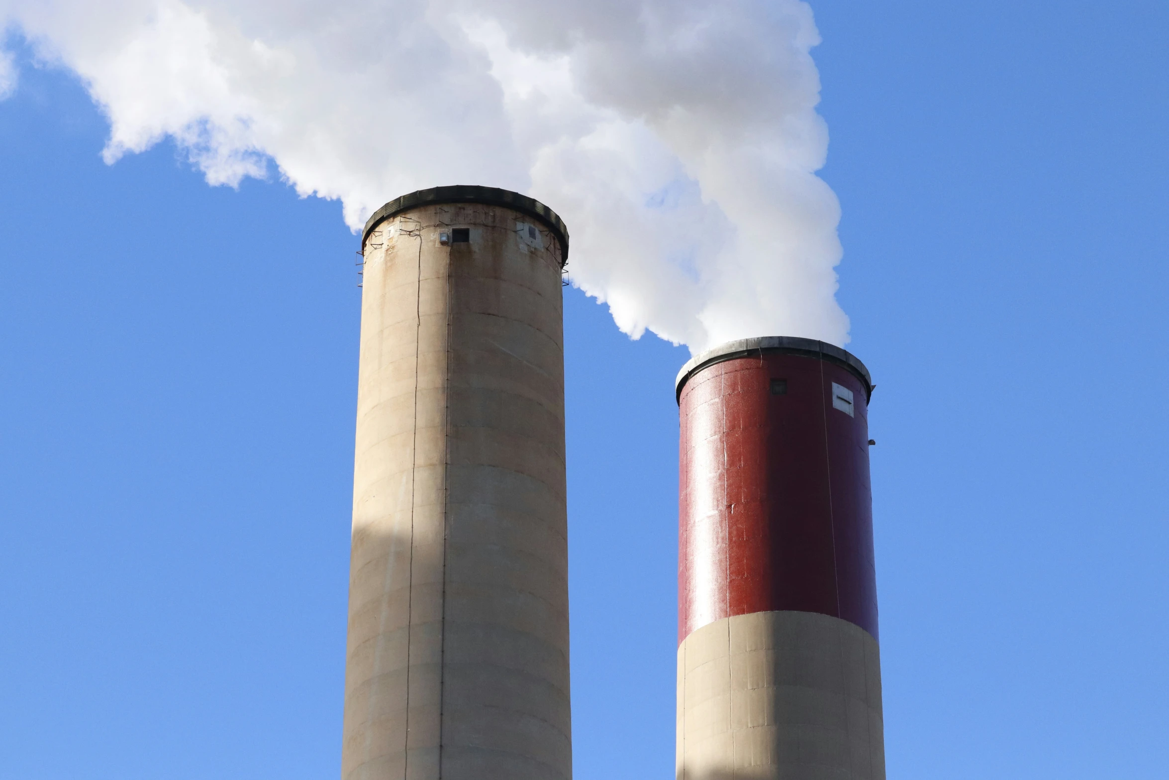 two chimneys emit steam in the air