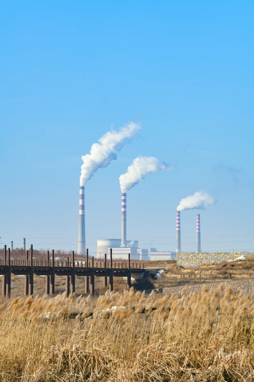 steam pipes emit from the stacks of smoke at a factory