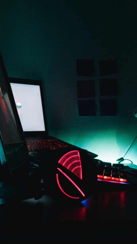 a laptop computer sitting next to a wall with a neon light