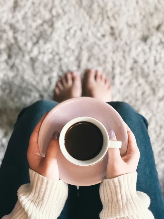 a person holding up a plate with food and a cup of coffee