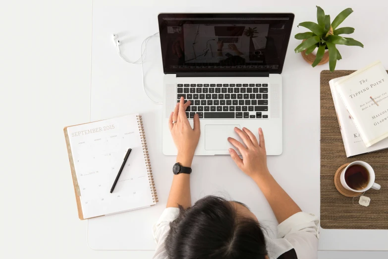 a person working on a laptop next to a cup