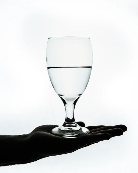 an outstretched hand holding a partially filled glass of water