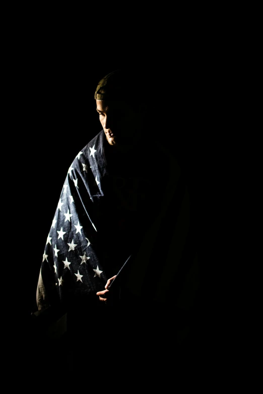 a man in the dark holding a blanket