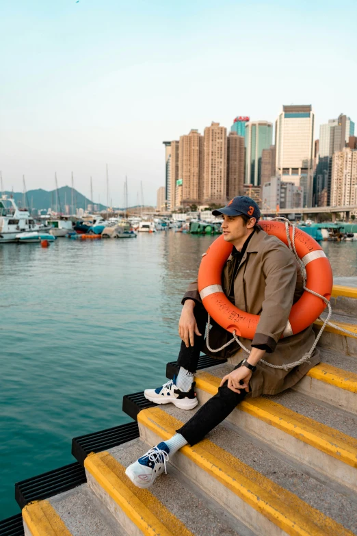 a person sitting on the edge of the steps in front of a body of water