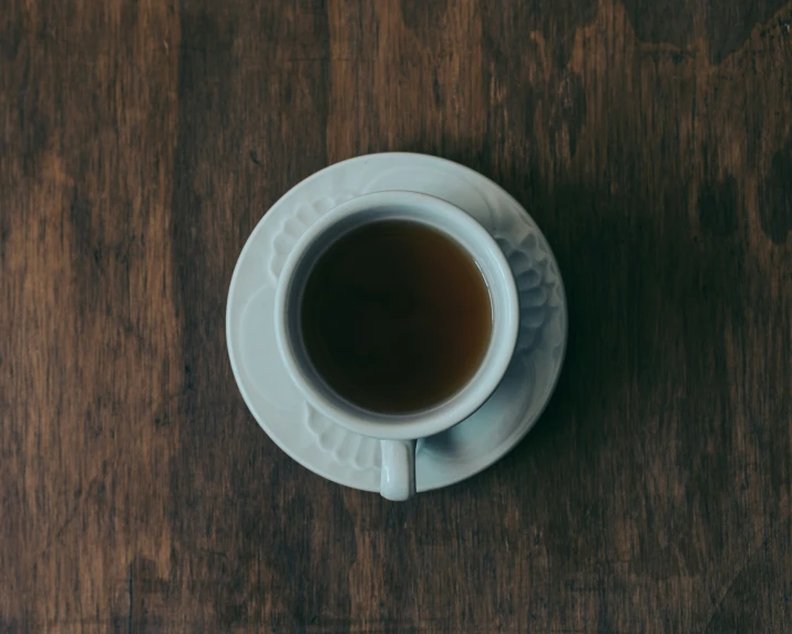 a cup of black tea sitting on top of a wooden table