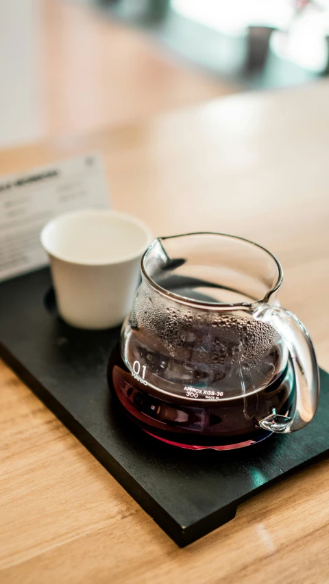 a small glass cup sitting on a wooden plate