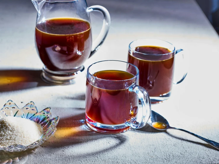 three glasses filled with liquid are next to a bowl and spoon