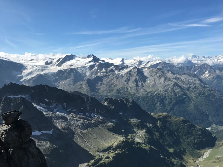 the man is standing on a mountain with his arms raised