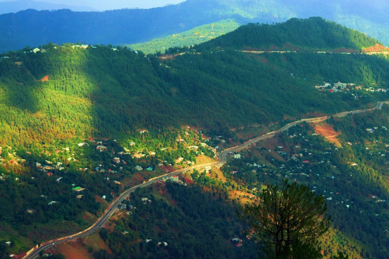 an aerial view shows a winding mountain road with houses on the hill