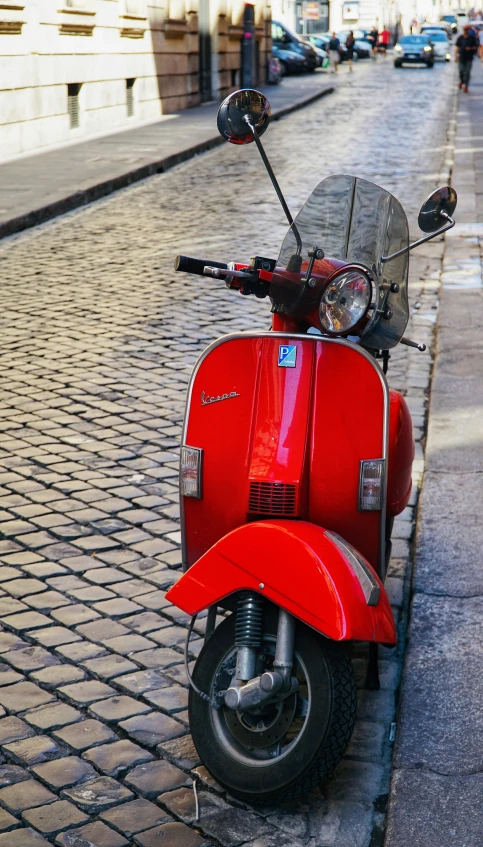 a red scooter parked on the side of the street