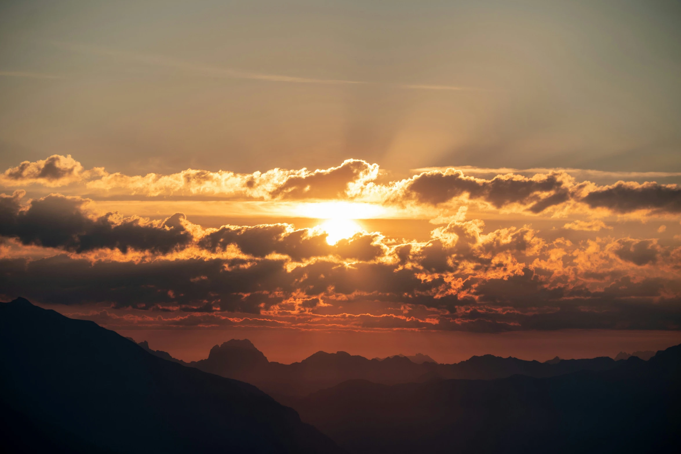 a large sun shining behind clouds in the sky