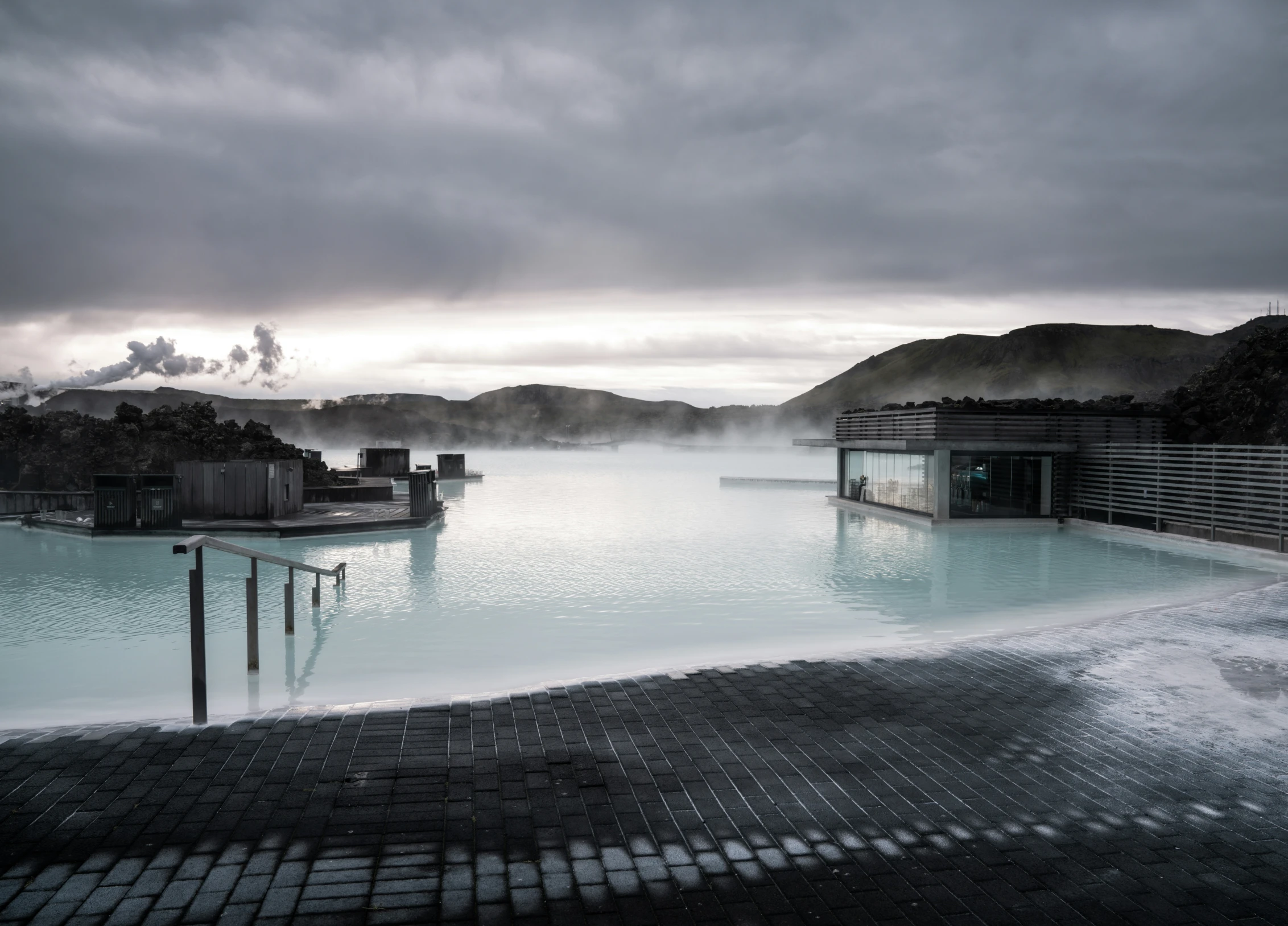 a large swimming pool next to a wooden pier under a cloudy sky