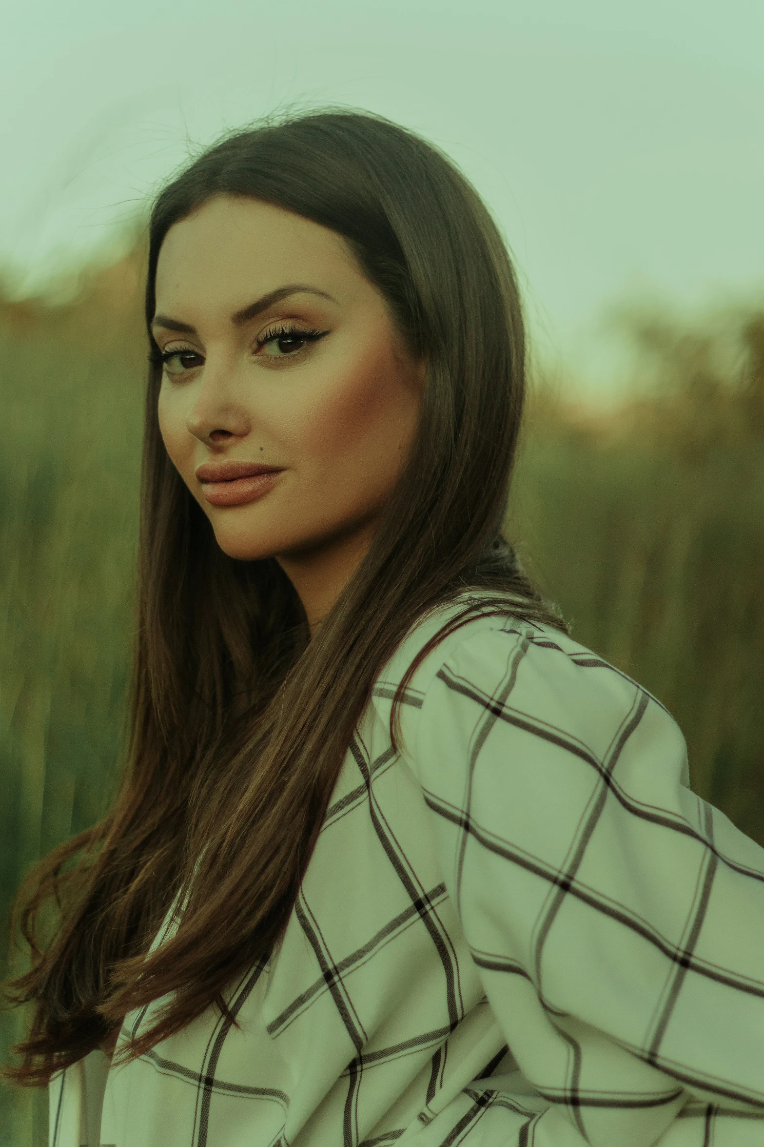 woman standing in a field of grass wearing a white and black jacket