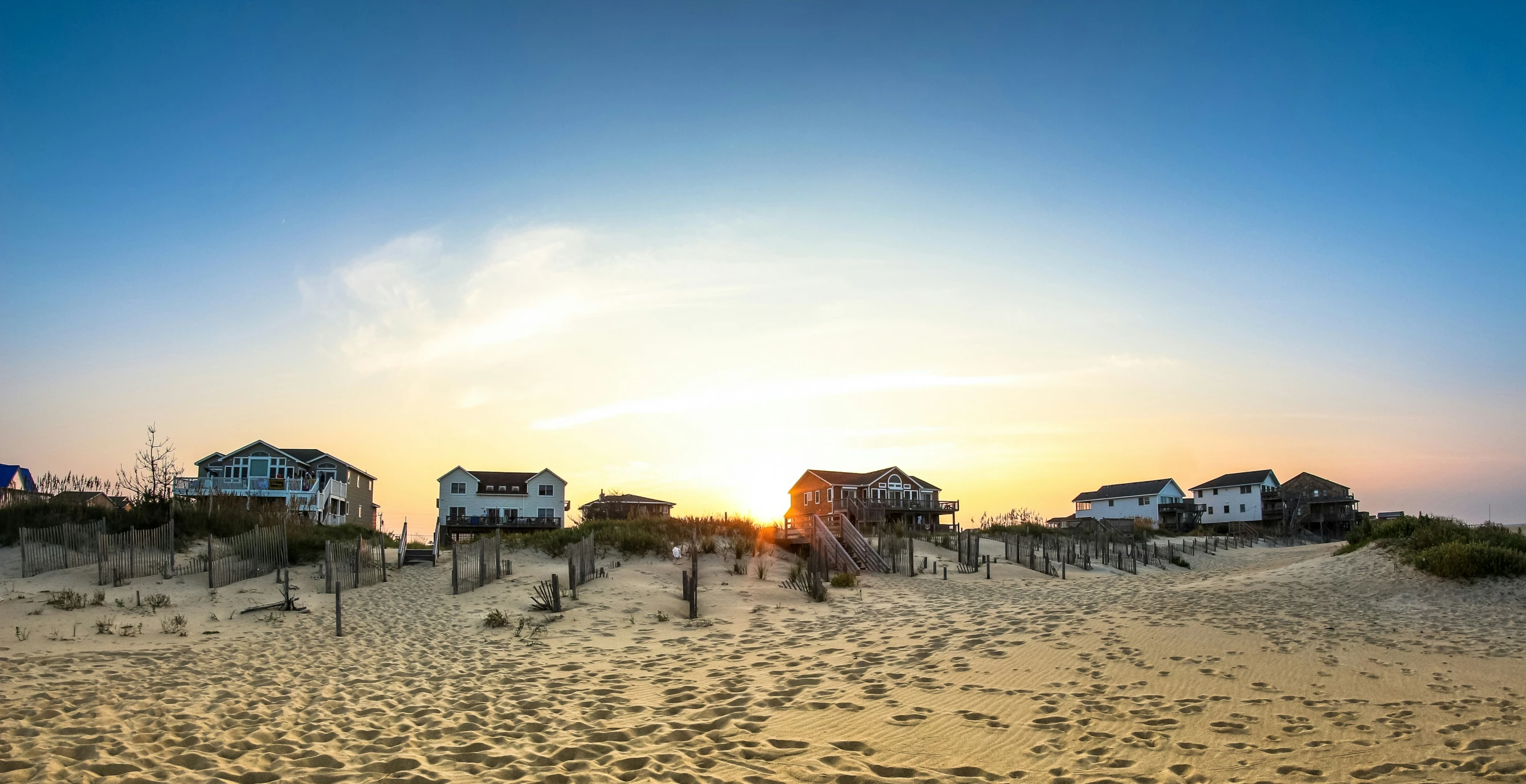 houses on a sandy beach at sunset