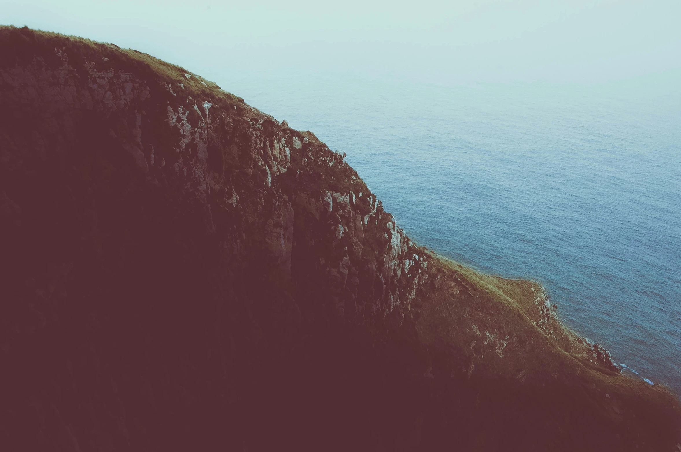 a rocky hill overlooking the ocean, with the cliffs partially hidden